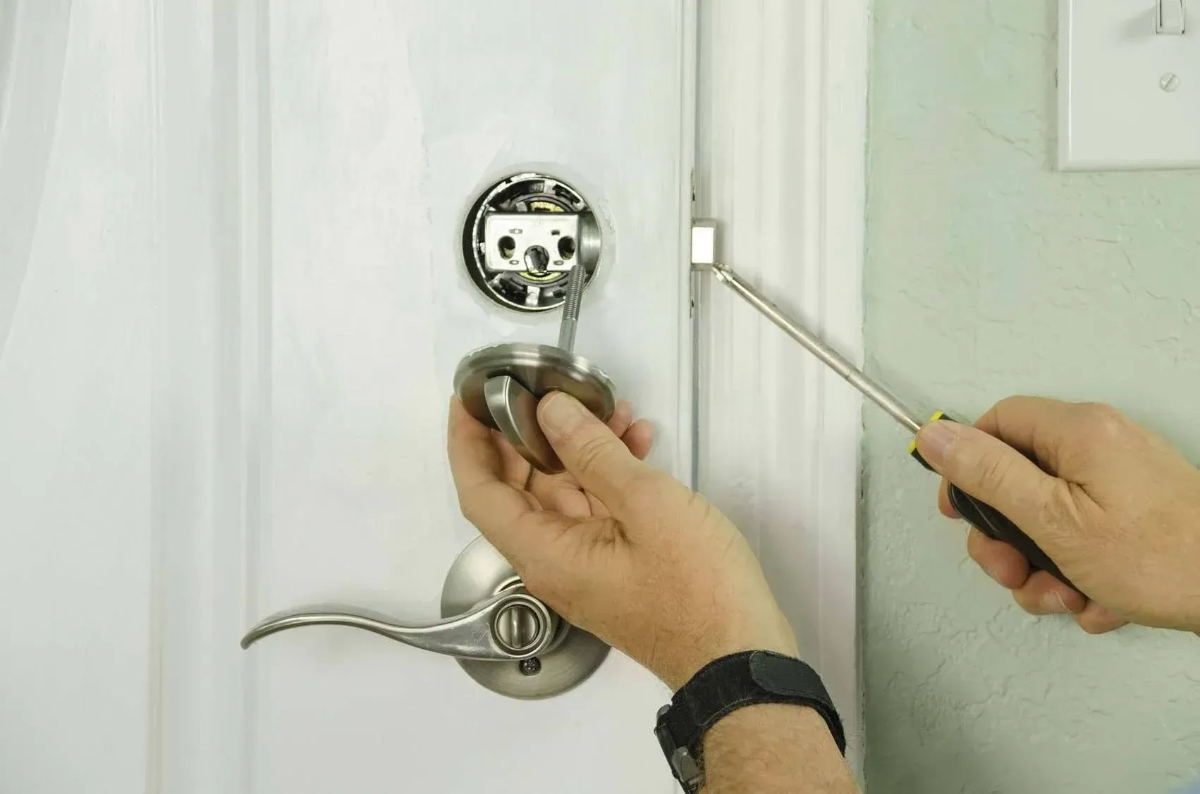 Lock-Tech technician fitting a lever handle lock to an interior door with a screwdriver